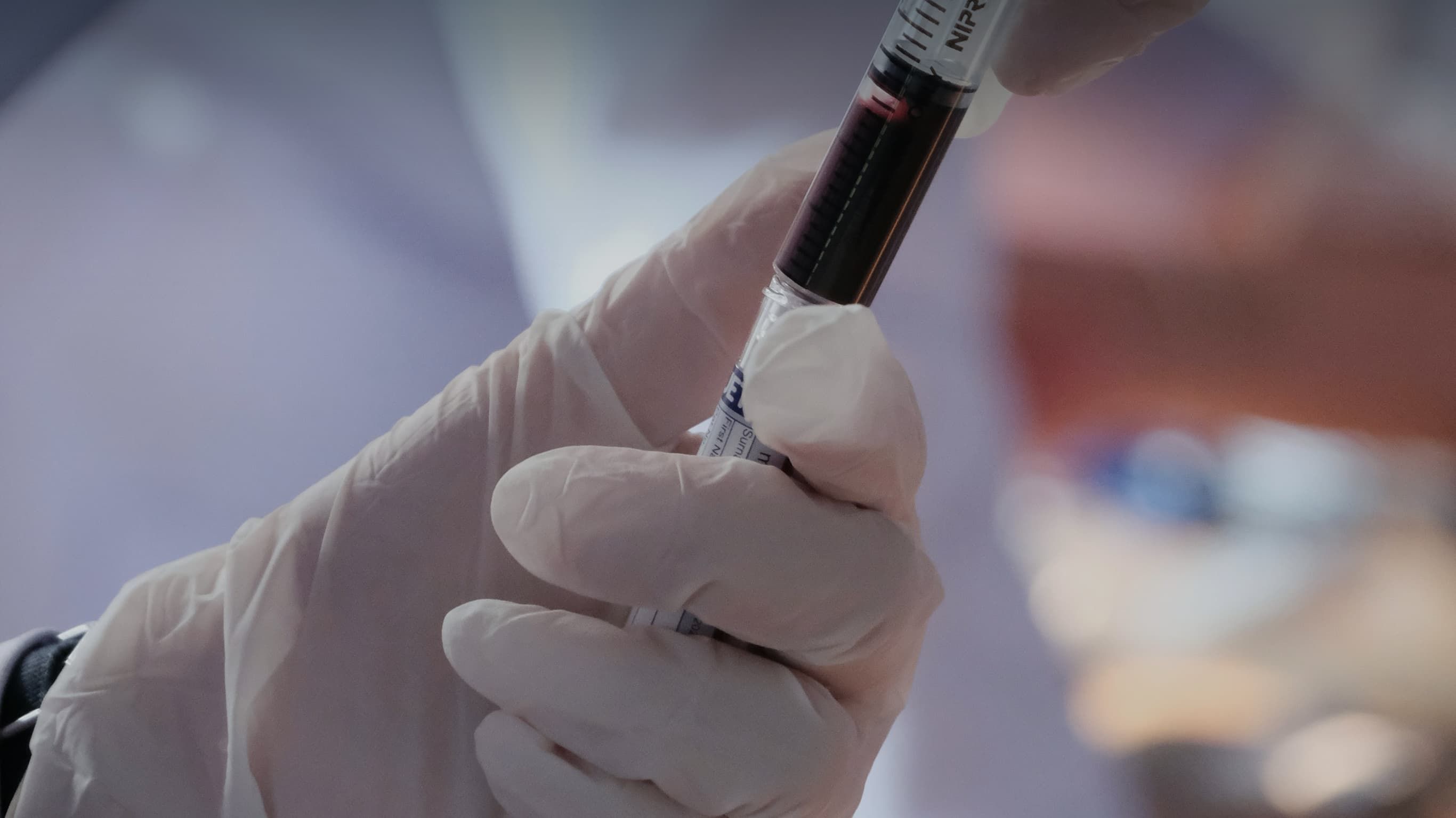 Gloved hands drawing blood into a syringe for regenerative therapy preparation